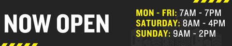A black promotional banner with bold white text reading 'NOW OPEN' and yellow and white operating hours for Monday through Sunday, with small yellow caution stripes in the corners.